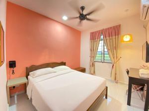 a bedroom with a white bed and a ceiling fan at Besut Guesthouse in Kuala Besut