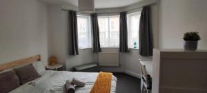 um quarto com uma cama e duas janelas em Bright & Chilled DB room with own bathroom! em Londres