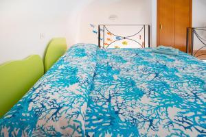 a bed with a blue comforter on top of it at Casa vacanze "Il Baffo e il Mare" in Cetara