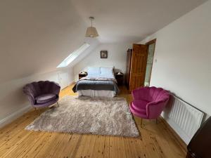 - une chambre avec deux chaises violettes et un lit dans l'établissement The Hazel Tree BnB, 
