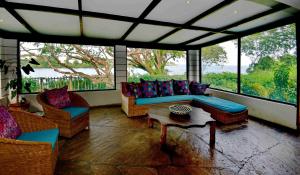 een woonkamer met banken, een tafel en ramen bij Mnarani Beach Club in Kilifi