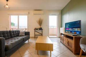 a living room with a couch and a flat screen tv at Le Capeyron - Parking - WIFI - Aéroport in Mérignac