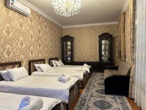 Habitación con 4 camas y lámpara de araña. en Guest house Chehra, en Samarkand
