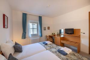 a bedroom with two beds and a desk with a television at Villa Fontana in Trogir