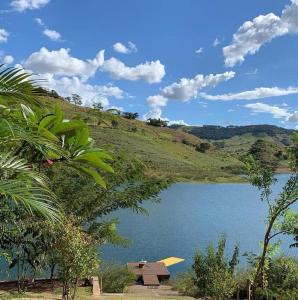 a lake with a house on the side of a hill at Rancho Morro do Cristo - Ribeirão Claro PR in Ribeirão Claro