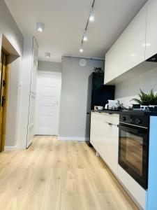 cocina con armarios blancos y suelo de madera en Apartament pod Zamkiem, en Szczecin