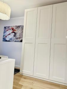 dos armarios blancos en una habitación con una pintura en Apartament pod Zamkiem, en Szczecin