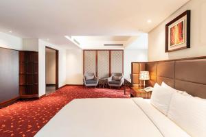 a hotel room with a bed and two chairs at Dhaka Regency Hotel & Resort Limited in Dhaka