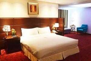 a hotel room with a large bed and a blue chair at Dhaka Regency Hotel & Resort in Dhaka +27 photos