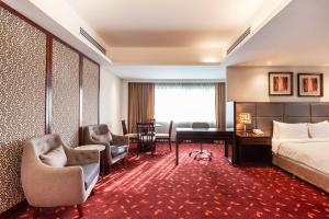 a hotel room with a bed and a desk and chairs at Dhaka Regency Hotel & Resort in Dhaka