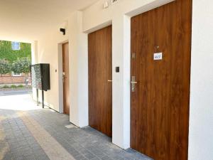 - un couloir avec deux portes en bois et une télévision dans l'établissement DMK Blue Apartment near Warsaw-Modlin Airport, à Nowy Dwór Mazowiecki