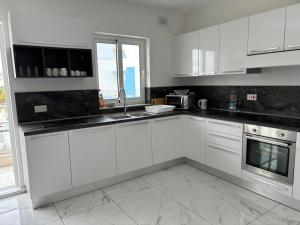a white kitchen with white cabinets and a window at Spacious and Cozy Apartment near St Julians - Short Let Apartments Malta in Is-Swieqi