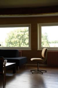 ein Wartezimmer mit zwei Fenstern und einem Stuhl in der Unterkunft Maison Maa, Maison principale, à 10 min de Saint-Valery-sur-Somme à pieds le long du canal in Boismont