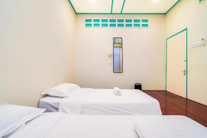 two beds in a room with white sheets at Dream & Wander Homestay in Ipoh