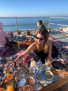 een vrouw aan een tafel met eten bij Hostel blue house Taghazout in Taghazout