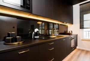 a kitchen with black cabinets and a sink at Black Pearl Apartment starówka in Elblag +14 photos