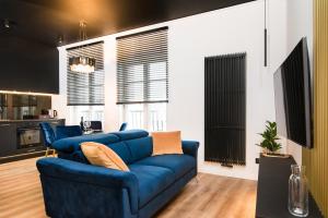 a living room with a blue couch and a kitchen at Black Pearl Apartment starówka in Elblag