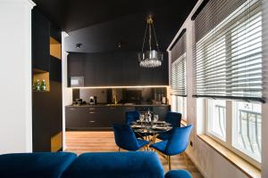 ein Wohnzimmer mit einem Tisch und blauen Stühlen in der Unterkunft Black Pearl Apartment starówka in Elblag