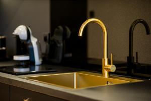 a yellow kitchen sink with two faucets on a counter at Black Pearl Apartment starówka in Elblag