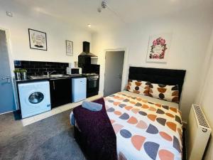 a bedroom with a bed and a kitchen with a washing machine at City Hideout - Centrally Located Studio in Liverpool