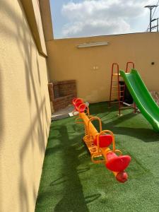 einen Spielplatz mit orangenen Stühlen und einer Rutsche in der Unterkunft شاليهات هدوء الشاطئ لبيوت العطلات in Ar Rukūbah