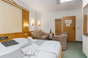 a hotel room with a white bed and two chairs at BmB Vollersode Monteurzimmer / Pension in Vollersode
