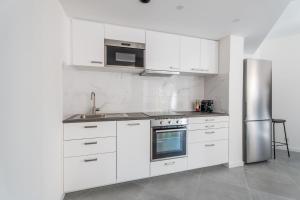 a kitchen with white cabinets and a stainless steel refrigerator at Modernity & Comfort Downtown Aix en Provence in Aix-en-Provence