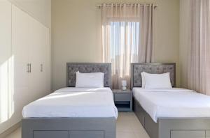 a bedroom with two beds with white sheets and a window at Vesta - El Gouna Residence in Hurghada