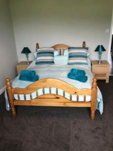 a bedroom with a wooden bed with blue pillows at Inishroel Cottage in Campbeltown