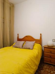 un lit avec une couverture jaune et une tête de lit en bois dans l'établissement Royal Luxe Terrace Sierra Subbetica, à Carcabuey