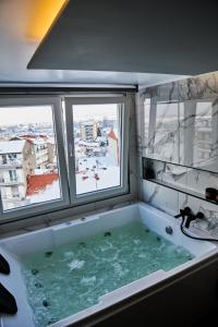 a bath tub in a room with two windows at The Skyline Suite in Florina