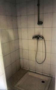 a shower with a hose in a white tiled bathroom at Tatys homestay in Dar es Salaam