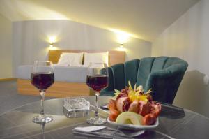 Rosse Hotel في إسنيورت: طاولة مع صحن من الفاكهة وكأسين من النبيذ