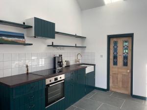 una cocina con armarios verdes y una puerta en Tresahor Studio, en Falmouth