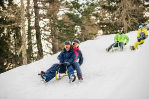 Un gruppo di persone sedute su una slitta nella neve di Dolomites Smart Holidays a Valdaora