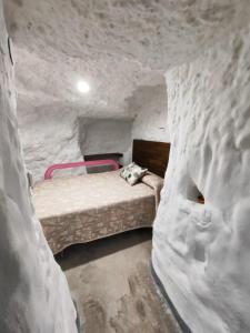 um pequeno quarto com uma cama numa caverna de pedra em Cueva de David 