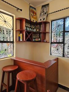 eine Bar mit zwei Hockern in einem Zimmer mit Fenstern in der Unterkunft B-MORE COMFORT STAY in Boma la Ngombe