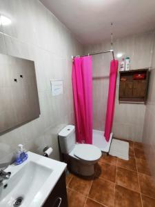uma casa de banho com um WC, um lavatório e uma cortina de duche rosa. em Cueva de David 