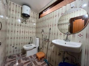 uma casa de banho com um lavatório, um WC e um espelho. em SNOWFLAKE Homestay em Gondla