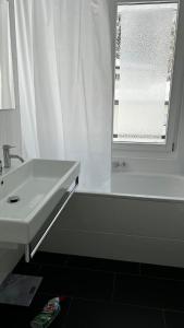 a bathroom with a sink and a tub and a window at Grüenipark Davos in Davos