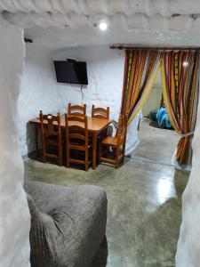 ein Wohnzimmer mit einem Tisch, Stühlen und einem TV in der Unterkunft Cueva de David 
