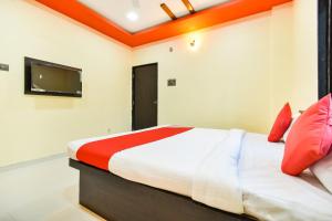 um quarto com uma cama com almofadas vermelhas e uma televisão em OYO Flagship Hotel Manish Inn em Aurangabad
