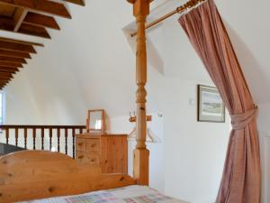 a bedroom with a wooden bed and a wooden staircase at Holly Cottage - 28140 in Boreland of Colvend