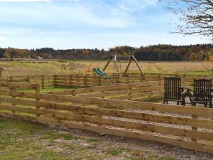 uma cerca de madeira com um parque infantil num campo em The Finch em Dyke