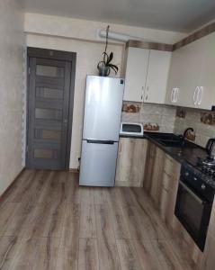 a kitchen with a white refrigerator and wooden floors at Ciocana apartament in Chişinău