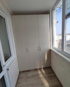 a room with white cabinets and a large window at Ciocana apartament in Chişinău