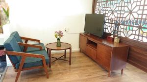 uma sala de estar com uma televisão, uma cadeira e uma mesa em Hoi An Four Seasons Villa em Hoi An