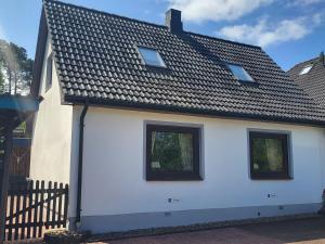 a white house with three windows and a black roof at Haus am Wald - Haus Nils und Haus Nele in Bark