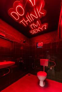 La salle de bains est pourvue de toilettes et d'un panneau de néon. dans l'établissement Whoopers Boutique Morjim, à Morjim