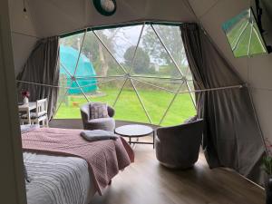 a bedroom with a large window in a tent at Benllech Glamping in Benllech